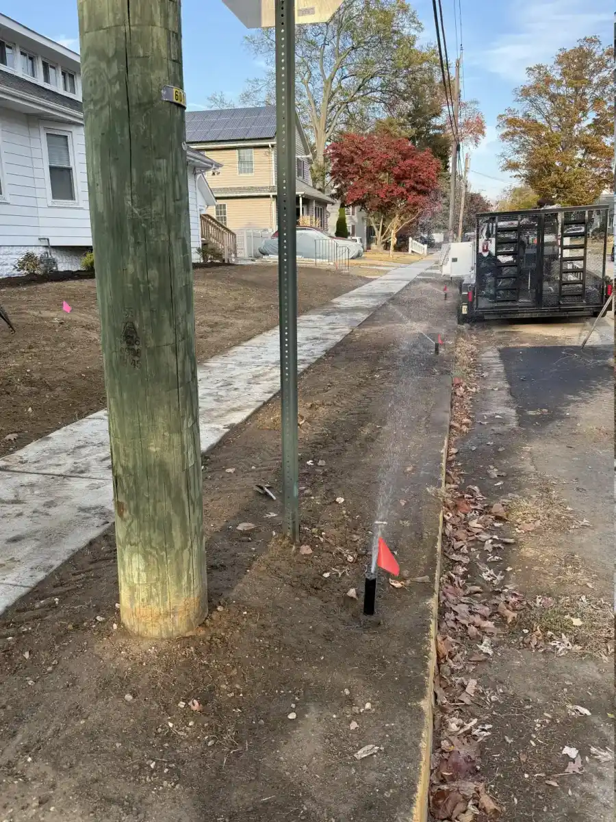 Sprinkler head being tested beside a sidewalk at a South Jersey property