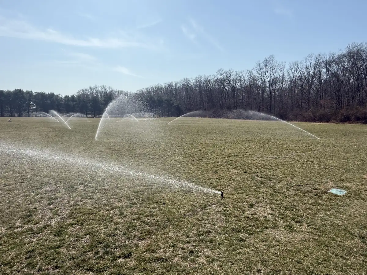 Athletic field irrigation system with sprinklers running at sunset