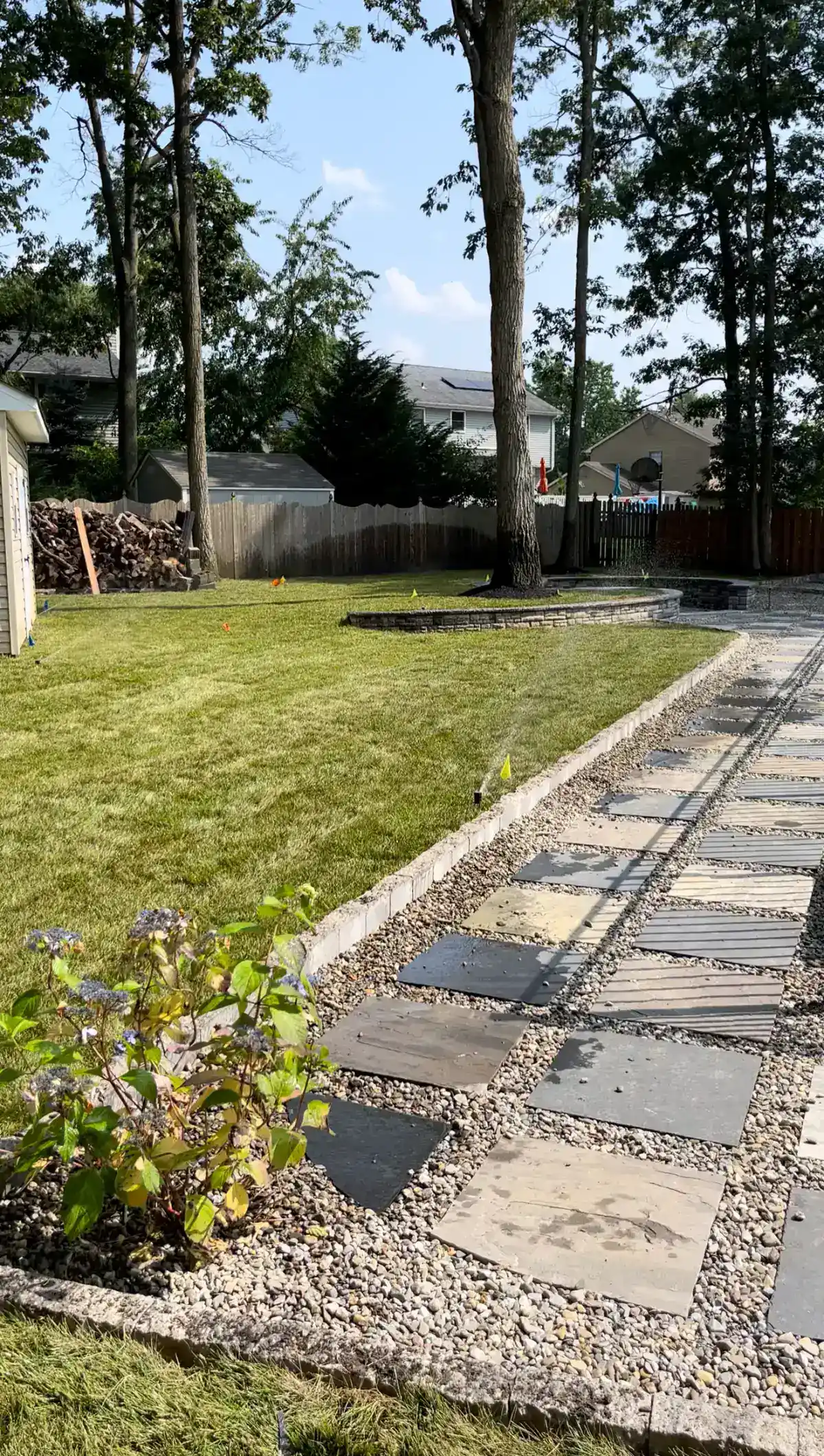 Sprinkler system watering a landscaped backyard with paver walkway in Camden County NJ